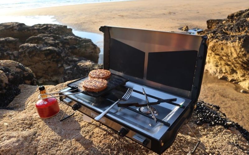 A portable double burner set near a shore for Best Portable Butane Stoves