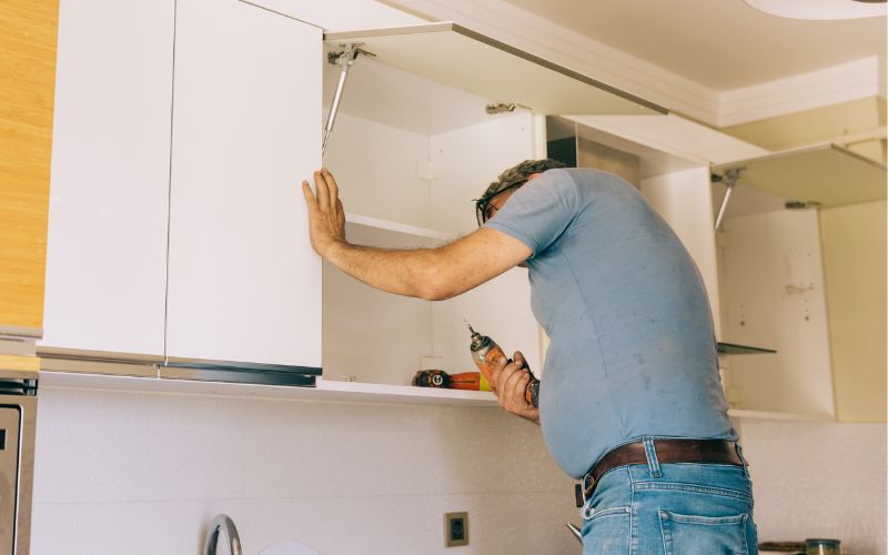 A man checking the inside of a cabinet in the kitchen